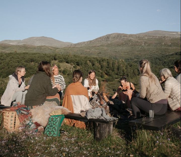 En gruppe samlet ute i kveldslys med fjell bak