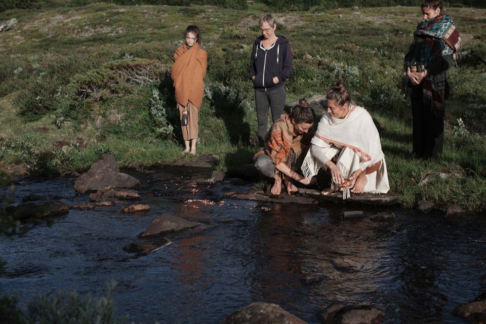 En gruppe står ved en fjellbekk