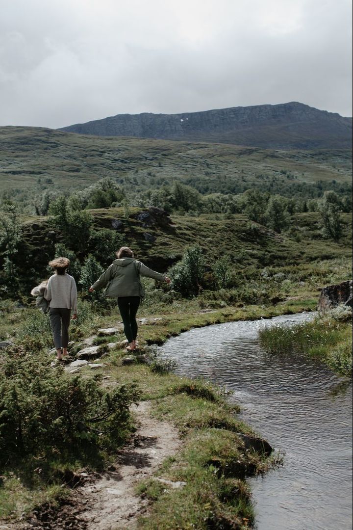 To personer går langs en bekk i fjellet